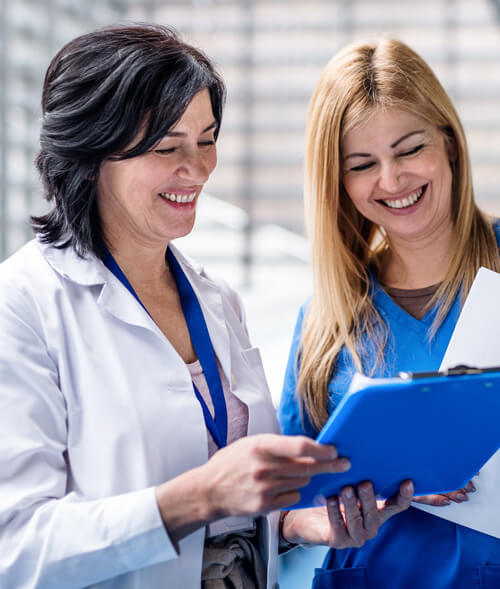 Two female doctors smiling and reviewing a positive report, illustrating the effectiveness of our Medical LED Light Therapy for sun-damaged skin